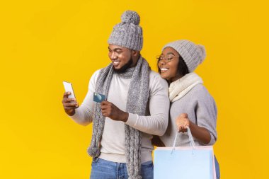 Genç siyah çift telefon ve kredi kartıyla online alışveriş yapıyor.