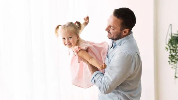 Щаслива маленька дочка літає в обіймах тата — стокове фото