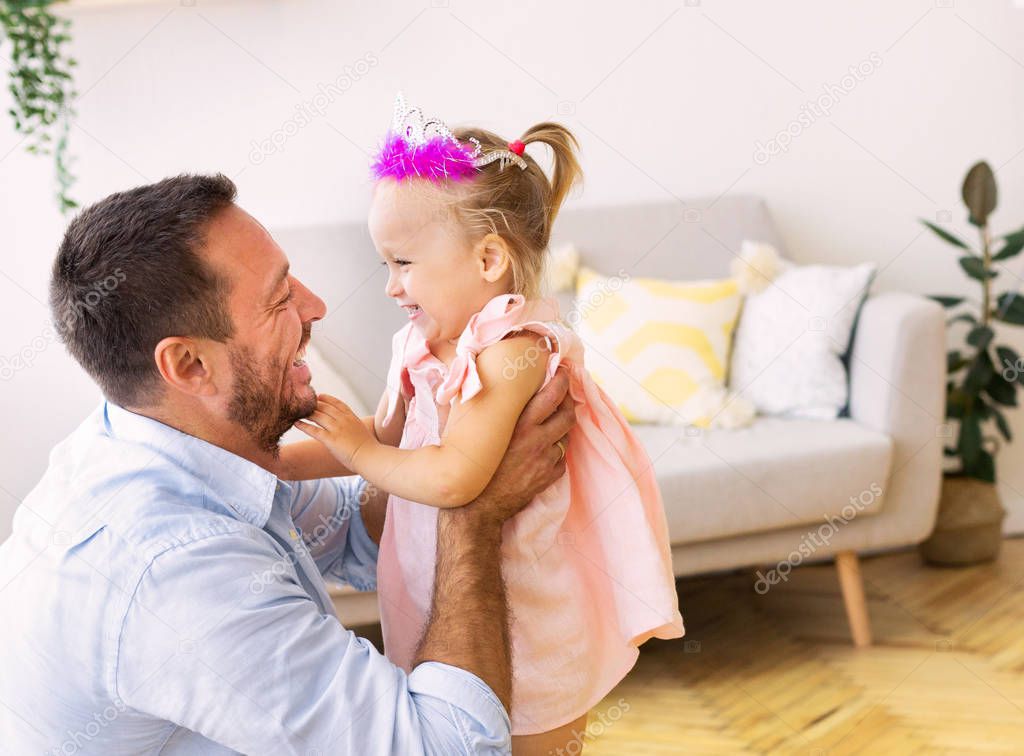 Dad babysitting his daughter in pink crown