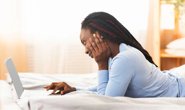 Afro-Amerikaanse dame werkt op laptop zittend in bed, Panorama — Stockfoto