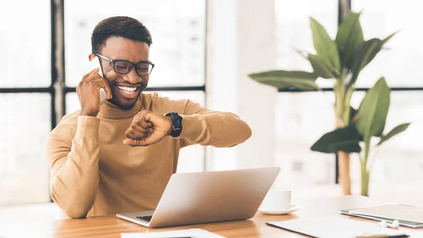 Gelukkig zwart guy kijken horloge praten op telefoon — Stockfoto