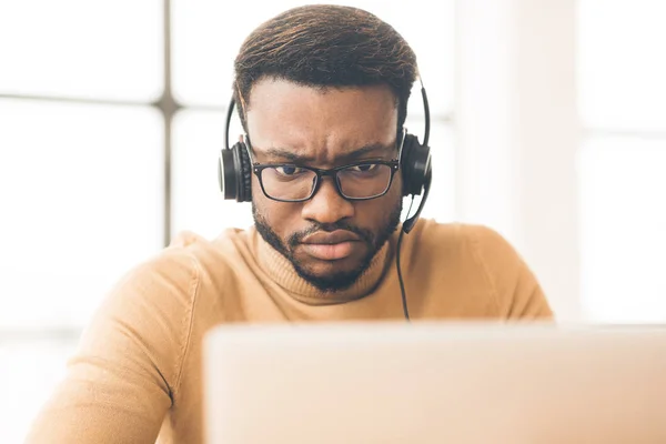 Geconcentreerde consultant met headset op zoek naar laptop — Stockfoto