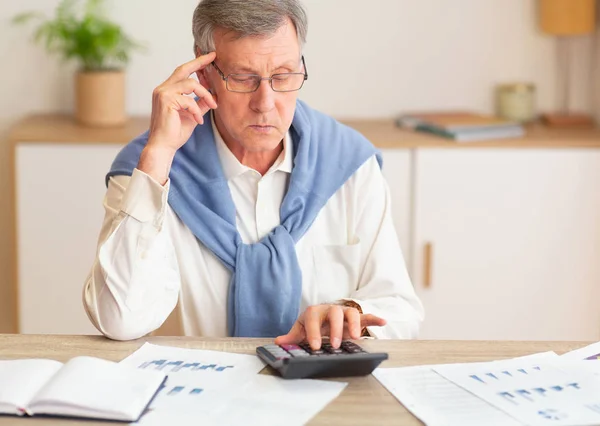Pensive Senior Man Using Calculator Seitting In Modern Office — Stock fotografie