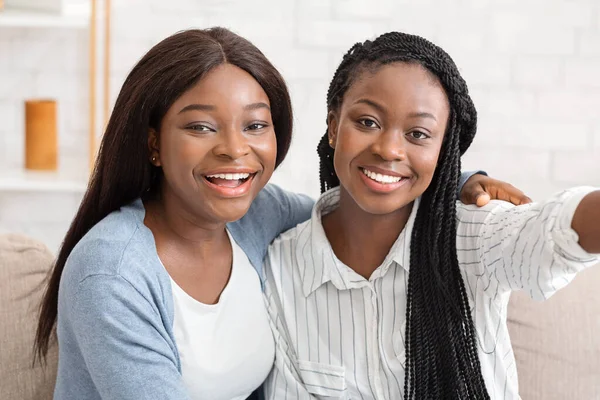 Dwie radosne czarne dziewczyny robiące selfie, spędzające czas razem w domu — Zdjęcie stockowe