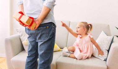 Baba, kızı için hediyesini arkasında saklıyor.