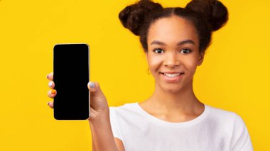Gülümseyen siyah genç yeni cep telefonunu gösteriyor