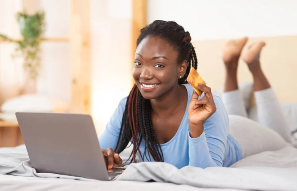 Vrouw Toont Credit Card met behulp van laptop winkelen Liggen in bed — Stockfoto