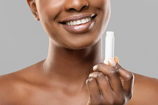 Bálsamo labial hidratante en manos de una mujer afroamericana irreconocible —  Fotos de Stock