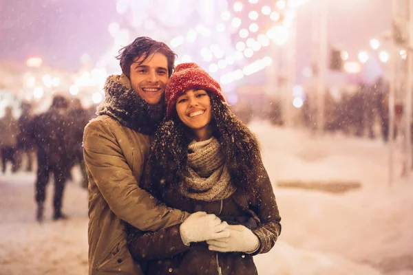 Casal abraço sorrindo para câmera de pé no mercado de Natal ao ar livre — Fotografia de Stock