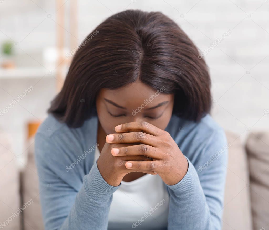 Depressed black woman sitting alone at home, feeling desperate