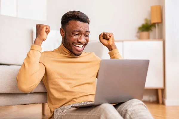 Afro Adam dizüstü bilgisayarı tutuyor iş başarısını kutluyor Evde oturuyor — Stok fotoğraf