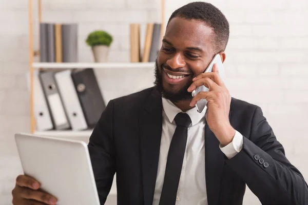 Χαρούμενος επιχειρηματίας που χρησιμοποιεί tablet ενώ μιλάει μέσω τηλεφώνου — Φωτογραφία Αρχείου