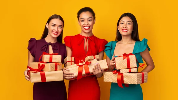 Tre ragazze multirazziali che tengono scatole di regali avvolte in piedi, colpo in studio — Foto Stock
