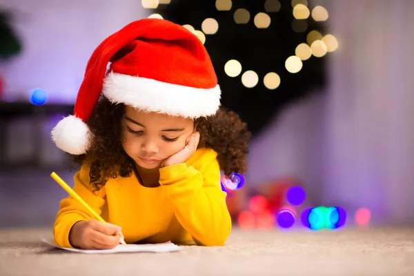 Concentrado pouco afro menina escrevendo carta para Papai Noel — Fotografia de Stock