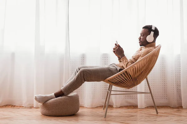 Millennial Afro Guy I hörlurar Använda Smartphone Sitter inomhus — Stockfoto