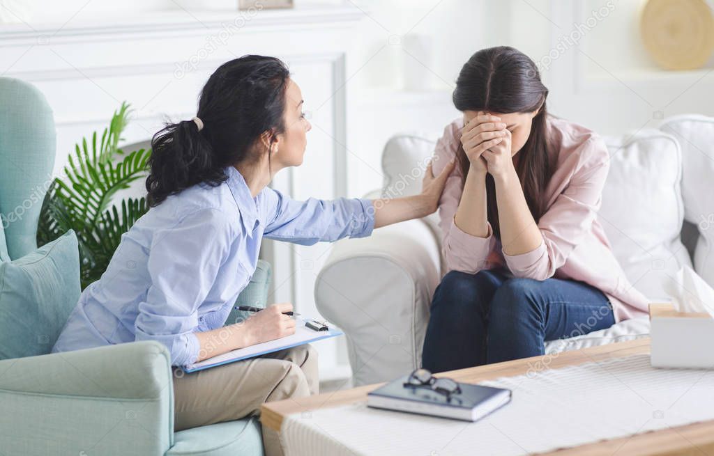 Young upset woman crying at therapist session, sharing her problem