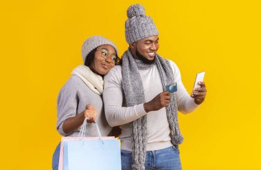 Kış Afrikalı çift online alışveriş yapıyor, akıllı telefon ve kredi kartı kullanıyorlar.
