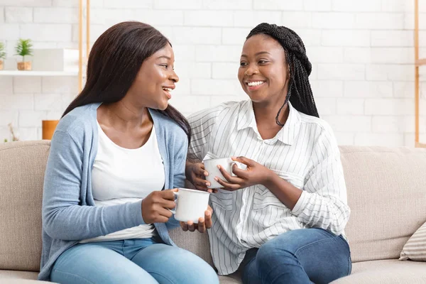 Счастливые черные девушки болтали, смеялись и пили кофе дома — стоковое фото