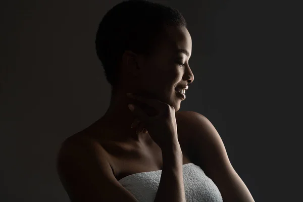 Havluya sarılı, karanlıkta duran güzel Afrikalı bir kızın portresi. — Stok fotoğraf