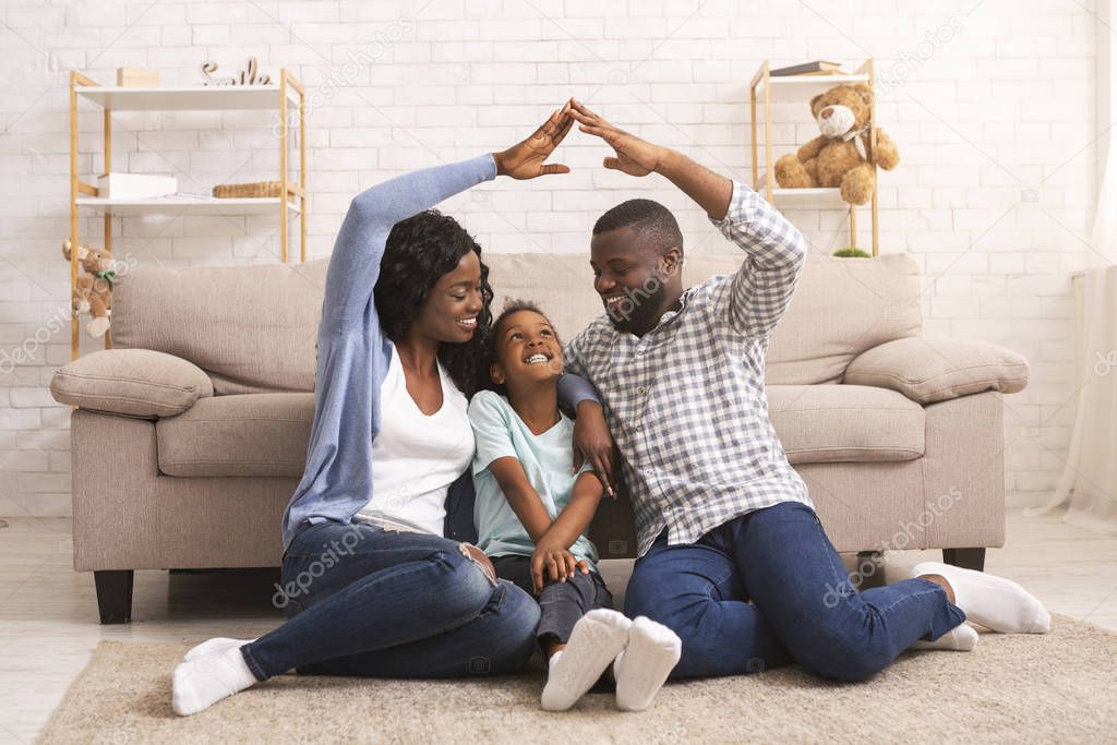 Black parents making symbolic roof of hands above little daughters head