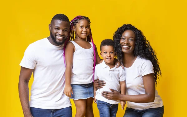 Glimlachende zwarte ouders met hun twee kleine kinderen over gele achtergrond — Stockfoto