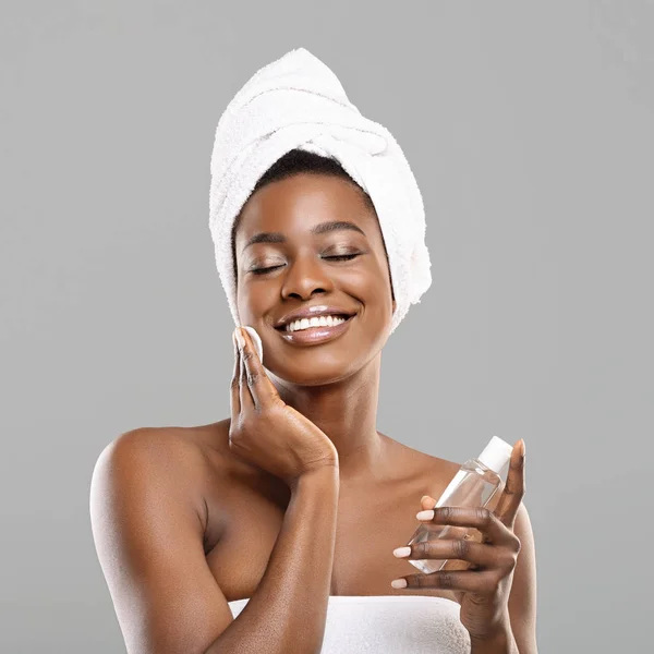 Африканская девушка чистит кожу хлопчатобумажными прокладками и тонером для лица после ванны — стоковое фото