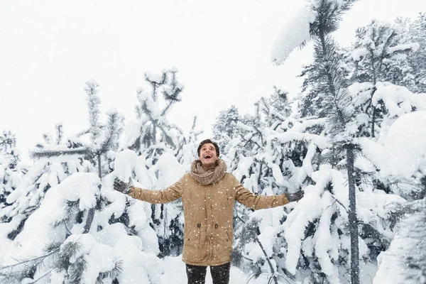 Hombre alegre disfrutando de invierno de pie extendiendo las manos en el bosque —  Fotos de Stock