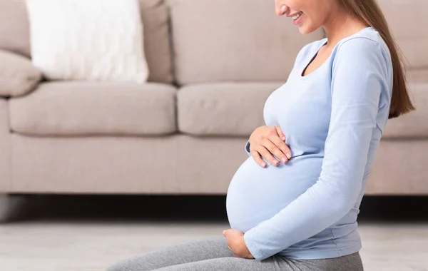 Крупный план счастливой беременной девушки, держащейся за руки на животе — стоковое фото