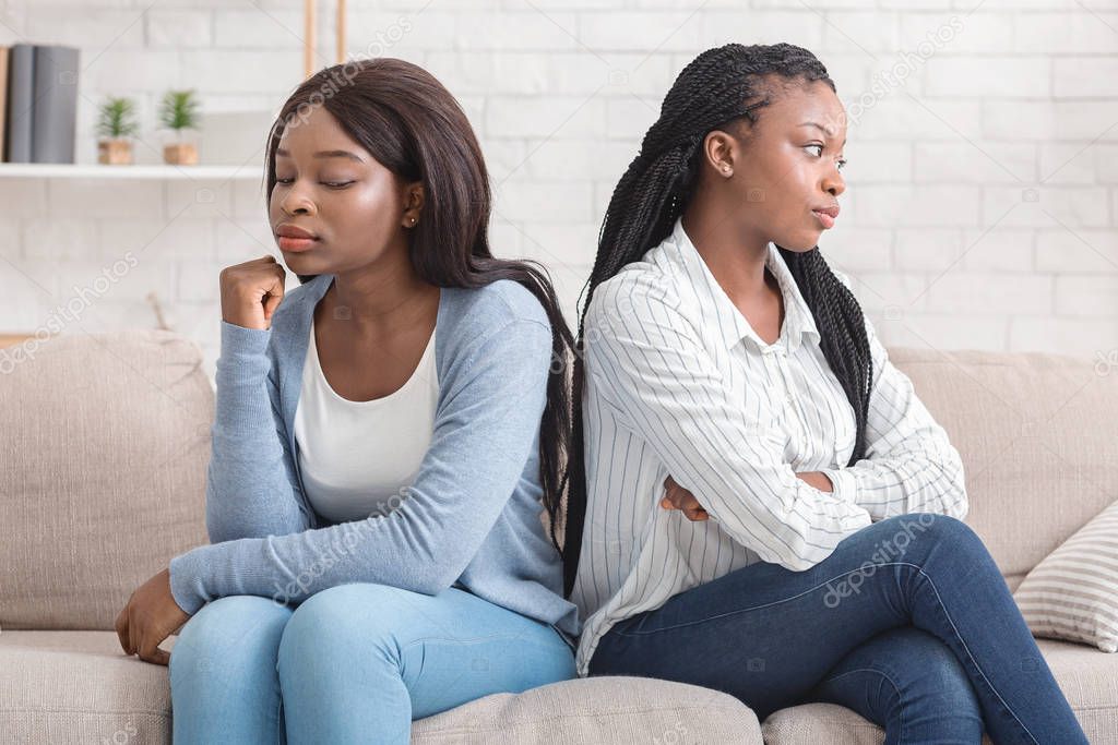 Offended girlfriends sitting back to back, ignoring each other after quarrel