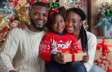 Noel ağacının yanında poz veren mutlu bir Afrikalı ailenin portresi.