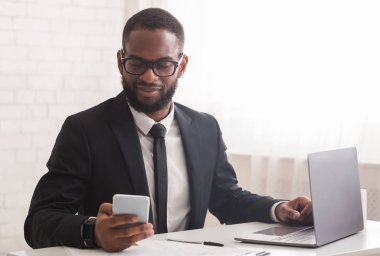 Yakışıklı iş adamı telefonda arkadaşlarıyla konuşuyor, ofiste çalışıyor.