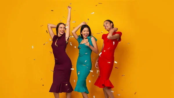 Trois filles danse avoir partie avec confettis sur jaune fond — Photo