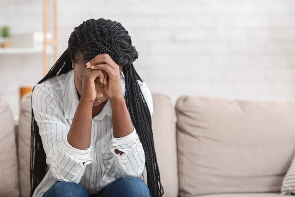 Desesperado menina negra sentado sozinho no sofá em casa — Fotografia de Stock