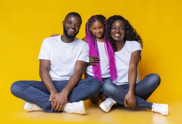 Pais negros felizes e sua filhinha sentados no chão juntos — Fotografia de Stock