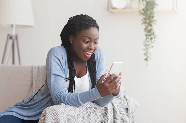 Heyecanlı siyah kadın akıllı telefondan iyi haberler alıyor. — Stok fotoğraf