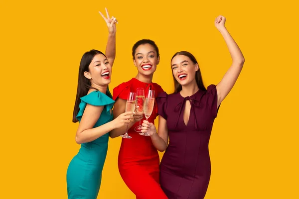 Tři modely cinkání brýle baví stojící nad žlutým pozadím — Stock fotografie