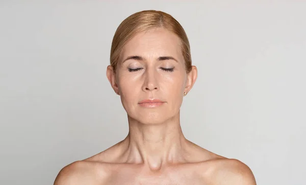 Mulher de meia-idade bonita com ombros nus e olhos fechados — Fotografia de Stock