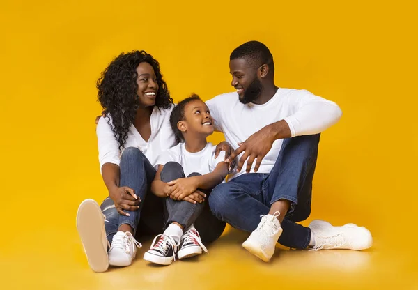 Zwarte ouders omhelzen met hun adopred dochter, zitten samen op de vloer — Stockfoto