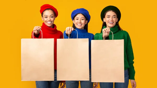 Three Girls Holding Paper Shopping Bags Standing, Yellow Background, Mockup — стокове фото
