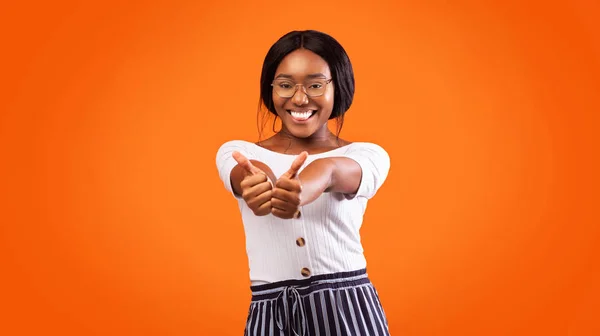 Afro donna gesturing pollice-up con entrambe le mani su sfondo arancione — Foto Stock