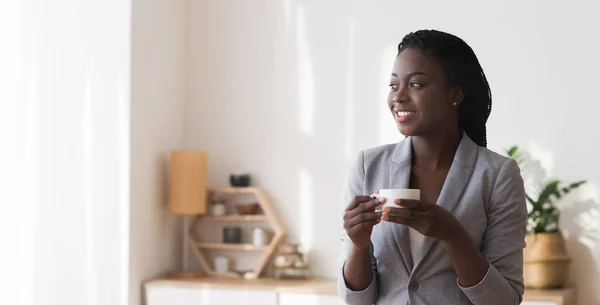 Портрет расслабленной афро-предпринимательницы с чашкой кофе в руках — стоковое фото