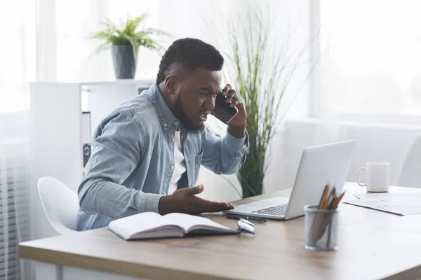 Απογοητευμένος επιχειρηματίας μιλάει στο τηλέφωνο, και κοιτάζοντας το φορητό υπολογιστή με θυμό — Φωτογραφία Αρχείου