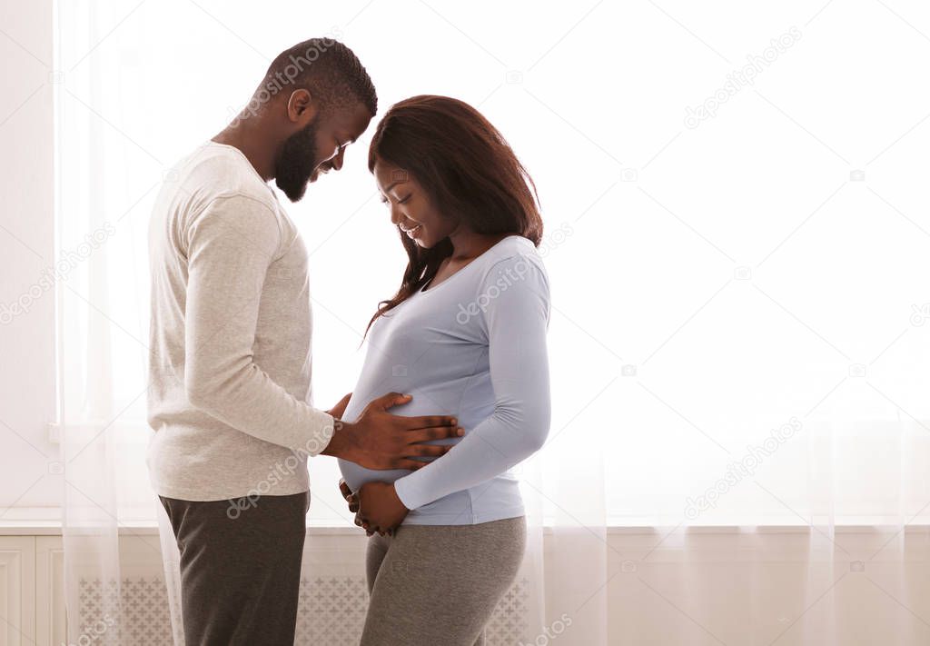 Loving man holding his wife belly, parenthood concept