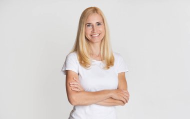 Mutlu orta yaşlı kadın çapraz kollarla poz veriyor.