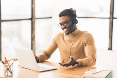 Kulaklıklı neşeli danışman müşteriyle konuşuyor.