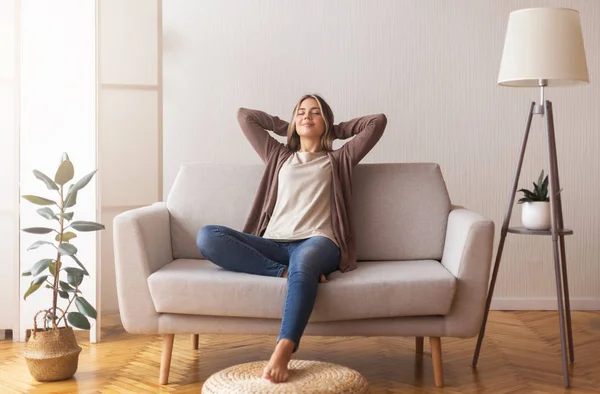 Chica milenaria relajándose en casa en el sofá, disfrutando del tiempo libre —  Fotos de Stock