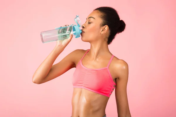 Deportiva mujer negra bebiendo agua de la botella de pie en el estudio — Foto de Stock