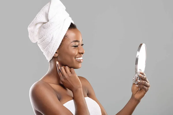 Привлекательная черная женщина держит зеркало и трогает свою идеальную мягкую кожу — стоковое фото