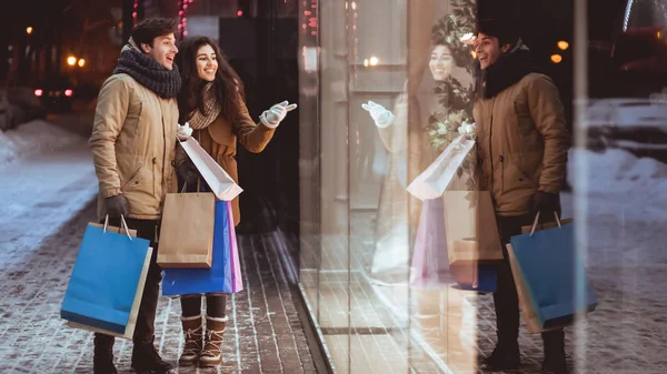 Chica señalando a escaparate de compras con novio en la ciudad, Panorama —  Fotos de Stock