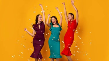 Sarı Arkaplan Üzerinde Düşen Konfeti Altında Dans Eden Üç Mutlu Kız